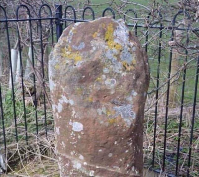 a very old stone protected by a railing. It is worn with no discernable writing on it a very old stone protected by a railing. It is worn with no discernable writing on it
